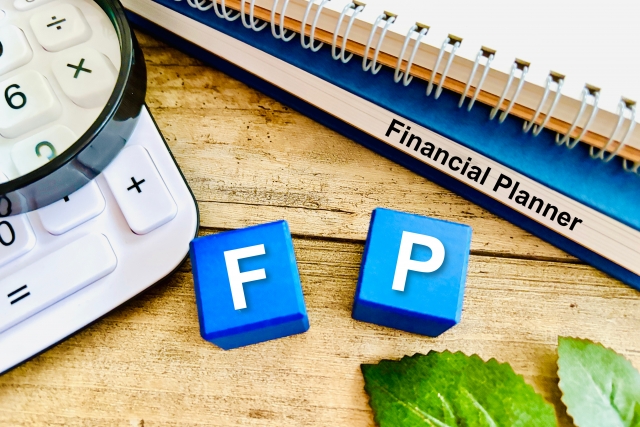 電卓と「Financial Planner」ノート、F・Pのブロック、ファイナンシャルプランナーのイメージ